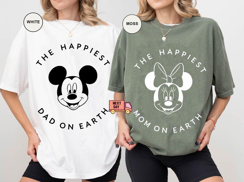May include: White and moss green t-shirts with Mickey and Minnie Mouse graphics. The white shirt says "The Happiest Dad on Earth" and the green shirt says "The Happiest Mom on Earth". Both shirts have black text and graphics.
