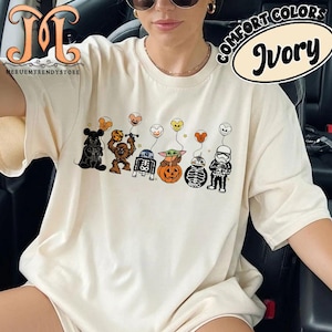 Op de afbeelding: Ivoor kleurig t-shirt met een Star Wars Halloween ontwerp. De afbeelding toont Darth Vader, Chewbacca, R2-D2, Baby Yoda, BB-8 en een Stormtrooper, elk met hartvormige ballonnen. Het shirt heeft ook de tekst "COMFORT COLORS" en "Ivory".