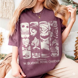 May include: A maroon short-sleeve t-shirt featuring a graphic print of characters from The Nightmare Before Christmas. The design consists of four vertical panels displaying Jack Skellington, Sally, Oogie Boogie, and other film characters.