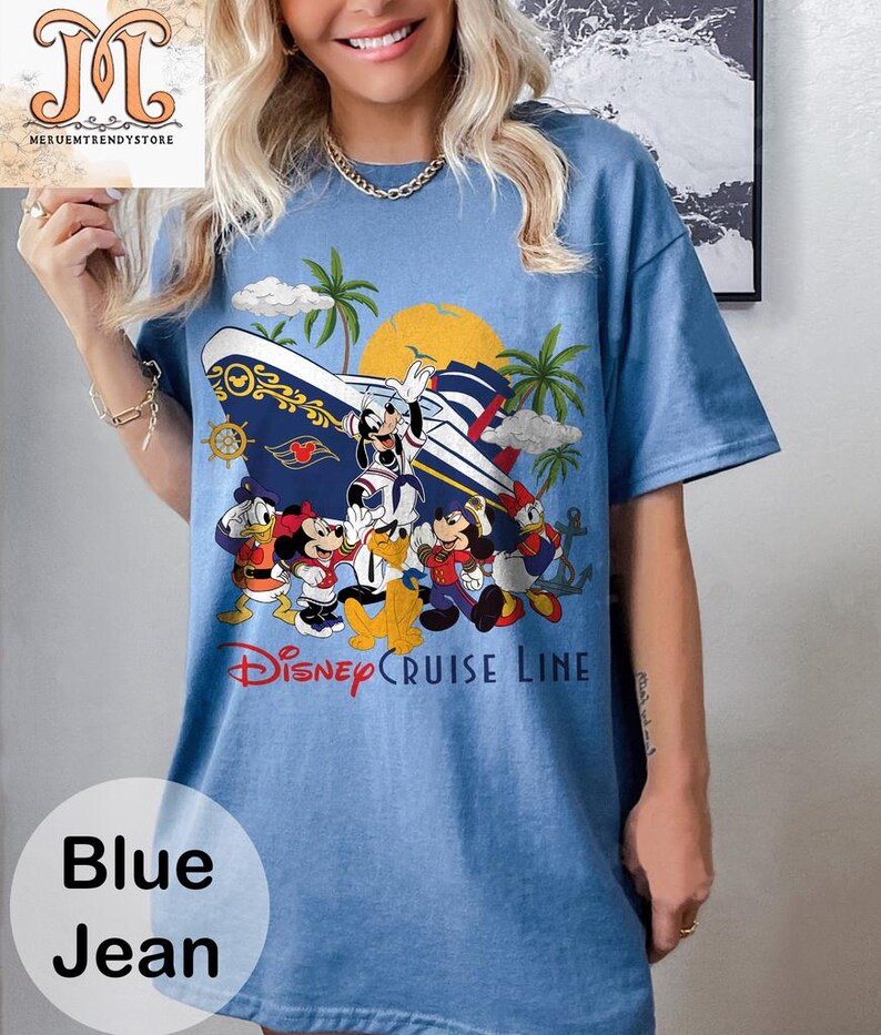 May include: Blue jean t-shirt featuring a colorful graphic of Disney characters on a cruise ship, with palm trees and a sun. The text "Disney Cruise Line" is displayed below the graphic. The shirt has short sleeves.