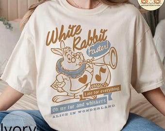 May include: White t-shirt with a vintage-style graphic of the White Rabbit from Alice in Wonderland. The graphic features the rabbit holding a trumpet and the text "White Rabbit Faster! Late for everything. Oh my fur and whiskers Alice in Wonderland."