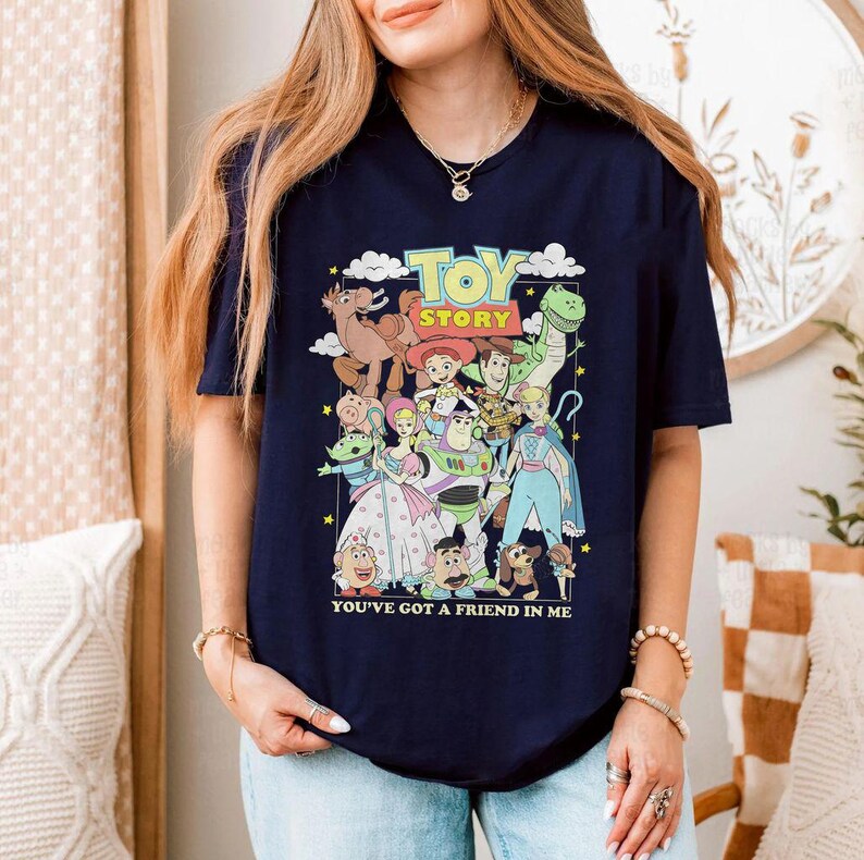 Puede incluir: Camiseta azul marino con un gr&aacute;fico colorido de personajes de la pel&iacute;cula "Toy Story". El dise&ntilde;o incluye a Woody, Buzz Lightyear y otros personajes. Tambi&eacute;n se muestra el texto "TOY STORY" y "YOU'VE GOT A FRIEND IN ME".