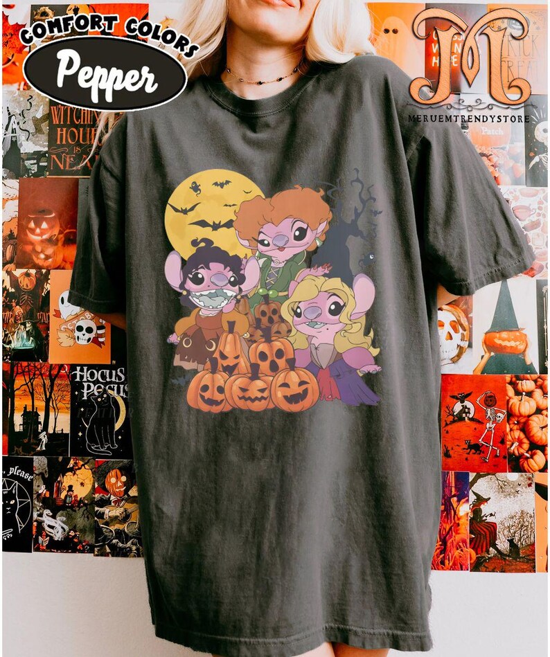 May include: Dark gray Comfort Colors Pepper t-shirt featuring a Halloween-themed graphic. The graphic includes cartoon characters, jack-o'-lanterns, a full moon, and bats. The shirt has the text "Comfort Colors" and "Pepper" in an oval.