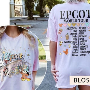 May include: Pink t-shirt featuring a graphic of Mickey Mouse and other Disney characters at Epcot. The back of the shirt displays the text "Epcot World Tour" and a list of countries and cities.