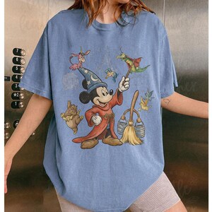 K&ouml;nnte beinhalten: Eine wei&szlig;e Keramik-Tasse mit schwarzem Henkel und dem Text "But First, Coffee" in fetter, schwarzer Schrift. Die Tasse steht vor einem verschwommenen Hintergrund. Die Tasse ist etwa 10 cm hoch.