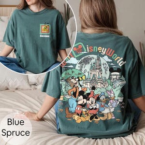 May include: Blue spruce t-shirt with a Disney World graphic on the back and a small Pluto graphic on the front pocket. The back graphic features Mickey, Minnie, Donald, and Goofy in front of a castle.