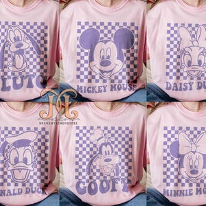 Puede incluir: Conjunto de seis camisetas rosas con un patr&oacute;n a cuadros y un personaje de dibujos animados en cada una. Los personajes son Pluto, Mickey Mouse, Daisy Duck, Donald Duck, Goofy y Minnie Mouse.