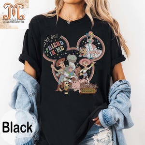 Puede incluir: Camiseta negra con un dise&ntilde;o de cabeza de Mickey Mouse con personajes de la franquicia de pel&iacute;culas Toy Story. El texto "I've got a friend in me" y "Woody's Roundup" est&aacute;n impresos en la camiseta.