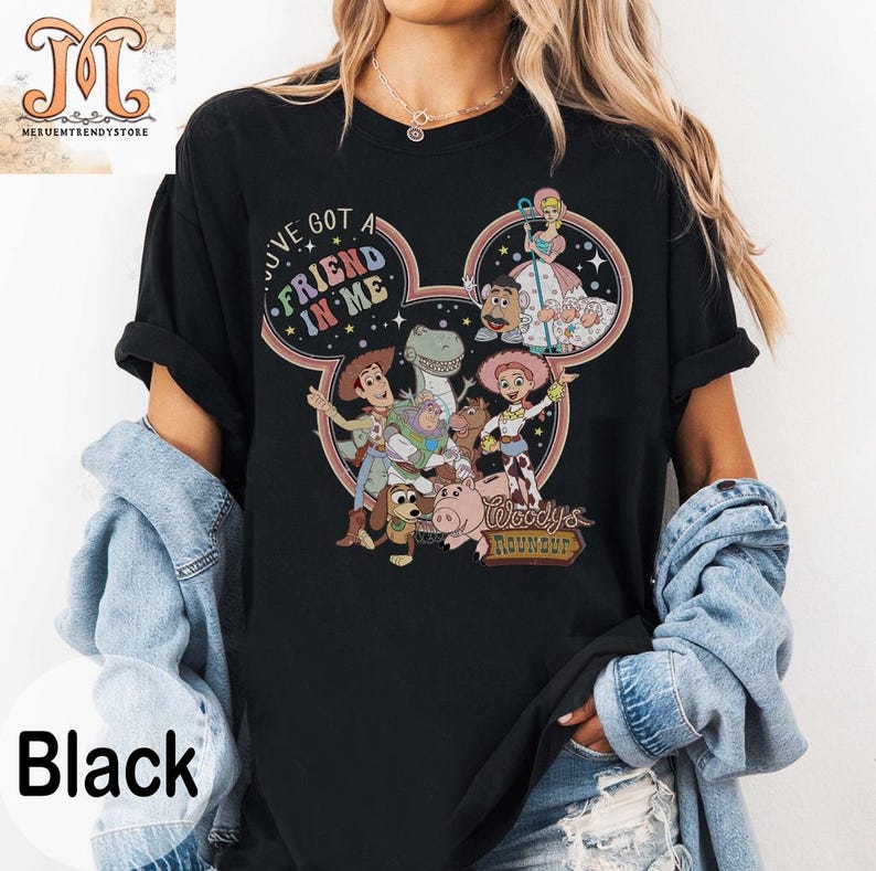 Puede incluir: Camiseta negra con un dise&ntilde;o de cabeza de Mickey Mouse con personajes de la franquicia de pel&iacute;culas Toy Story. El texto "I've got a friend in me" y "Woody's Roundup" est&aacute;n impresos en la camiseta.