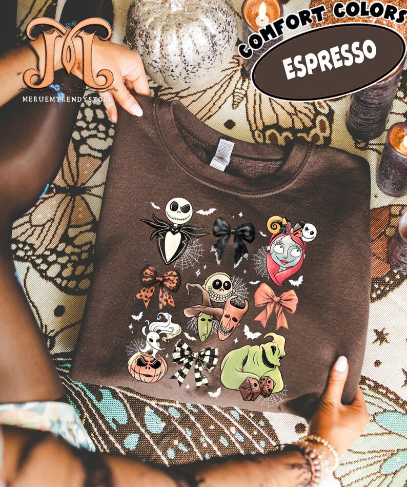Puede incluir: Sudadera marr&oacute;n oscuro con un dise&ntilde;o de personajes de Pesadilla antes de Navidad. El dise&ntilde;o incluye a Jack Skellington, Sally y otros personajes. La sudadera tiene las palabras "Comfort Colors" y "Espresso" impresas.