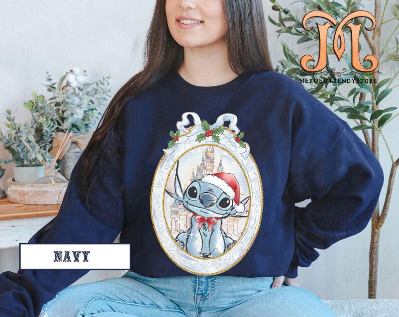 May include: Navy blue sweatshirt featuring a cartoon character wearing a Santa hat and a red bow tie, set against a castle backdrop within an ornate frame. The word "NAVY" is printed at the bottom.