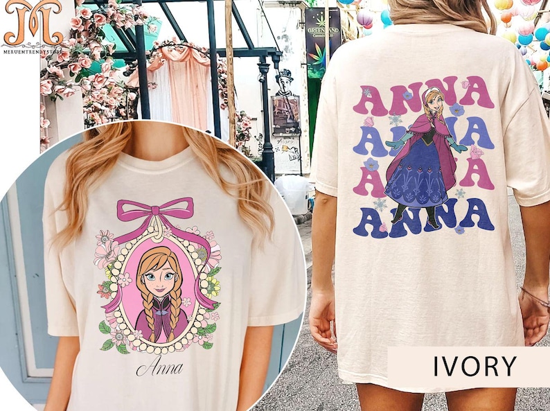 May include: Two ivory t-shirts with different designs featuring the character Anna from the movie Frozen. One shirt has a graphic of Anna in a pink frame with flowers and pearls. The other shirt has a graphic of Anna with the word "Anna" repeated four times in a retro font.