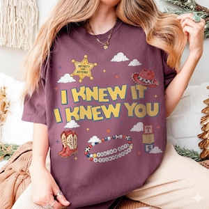May include: A maroon t-shirt featuring a yellow sheriff star with the text "INFINITY AND BEYOND," a red cowboy hat, a pair of red cowboy boots, a beaded bracelet with the text "YOU'VE GOT A FRIEND IN ME," and the text "I KNEW IT I KNEW YOU."