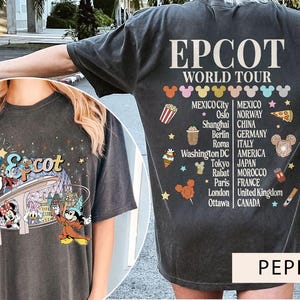 May include: A black t-shirt featuring a graphic of Mickey Mouse and friends at Epcot's World Showcase. The shirt also includes the text "Epcot World Tour" and a list of countries represented at the World Showcase.