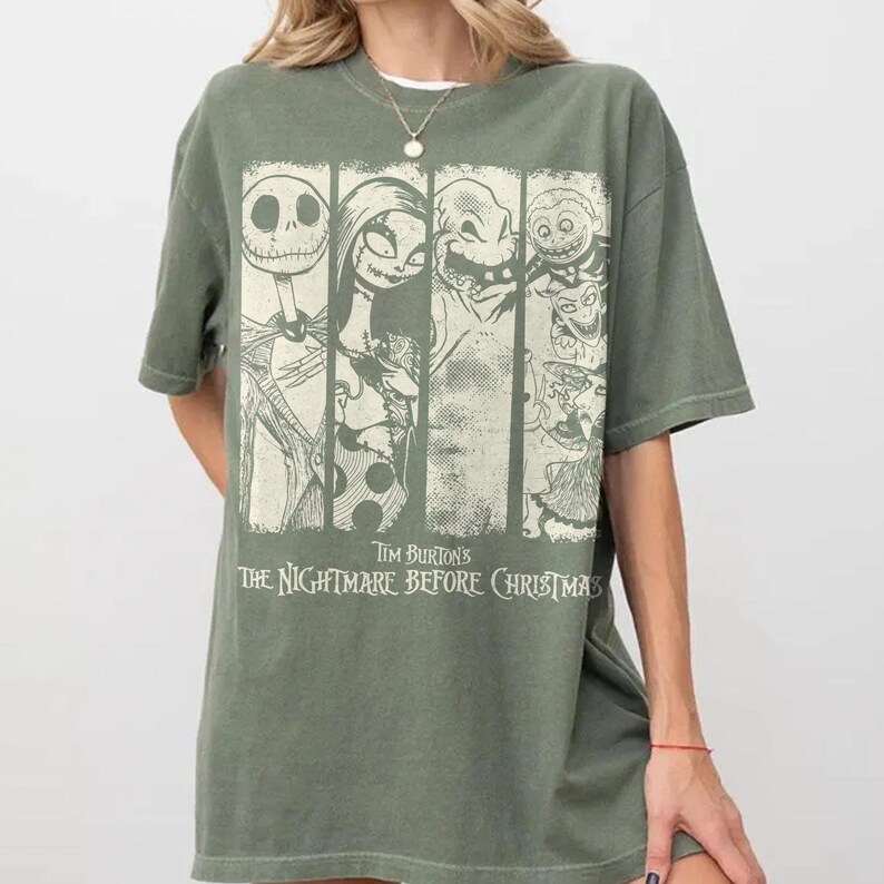 以下が含まれることがあります： オリーブグリーンの半袖Tシャツ。ティム・バートンの『ナイトメアー・ビフォア・クリスマス』のキャラクターがクリーム色のグラフィックでプリントされています。デザインは4つの縦パネルに分かれており、ジャック・スケリントン、サリーなどが描かれています。