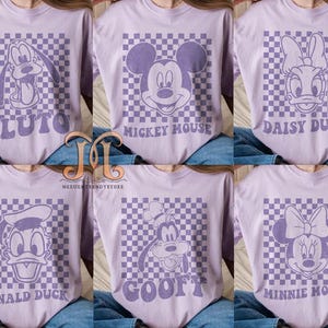 Puede incluir: Seis camisetas moradas con diferentes personajes de Disney en cada una. Los personajes son Pluto, Mickey Mouse, Daisy Duck, Donald Duck, Goofy y Minnie Mouse. Cada personaje est&aacute; sobre un fondo a cuadros.