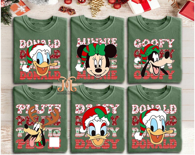 May include: Six green t-shirts featuring Disney characters in Christmas attire. Donald Duck, Minnie Mouse, Goofy, Pluto, and Donald Duck are depicted with festive hats and holiday-themed text. The shirts have a crew neck design.