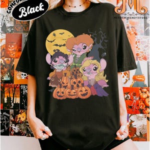 May include: Black t-shirt featuring a Halloween-themed graphic. The design includes cartoon characters resembling Stitch, dressed as the Sanderson sisters from Hocus Pocus, with pumpkins, a full moon, and bats. The shirt has the text "COMFORT COLORS Black".