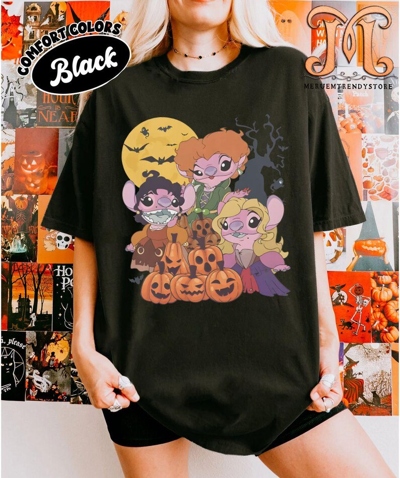 May include: Black t-shirt featuring a Halloween-themed graphic. The design includes cartoon characters resembling Stitch, dressed as the Sanderson sisters from Hocus Pocus, with pumpkins, a full moon, and bats. The shirt has the text "COMFORT COLORS Black".
