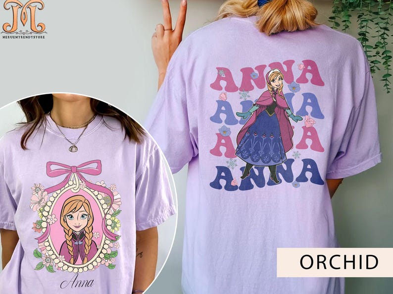 May include: Two purple t-shirts with different designs featuring the character Anna from the movie Frozen. One shirt has a graphic of Anna with the word "Anna" repeated five times. The other shirt has a graphic of Anna in a frame with the word "Anna" below the frame.