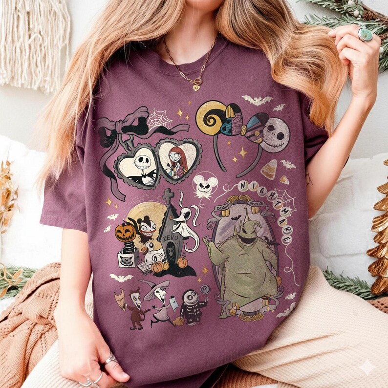 May include: A dark purple t-shirt featuring a graphic print of characters and motifs from The Nightmare Before Christmas, including Jack Skellington, Sally, Oogie Boogie, Zero, and various Halloween-themed icons like bats, pumpkins, and spiderwebs.