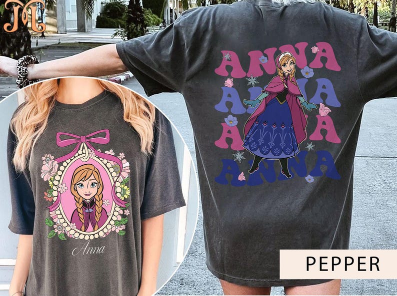 May include: Two gray t-shirts with a graphic print of Anna from Frozen. One shirt features a cartoon image of Anna in a frame with flowers and the text "Anna". The other shirt features a cartoon image of Anna in a blue and purple dress with the text "Anna" repeated in a retro font.