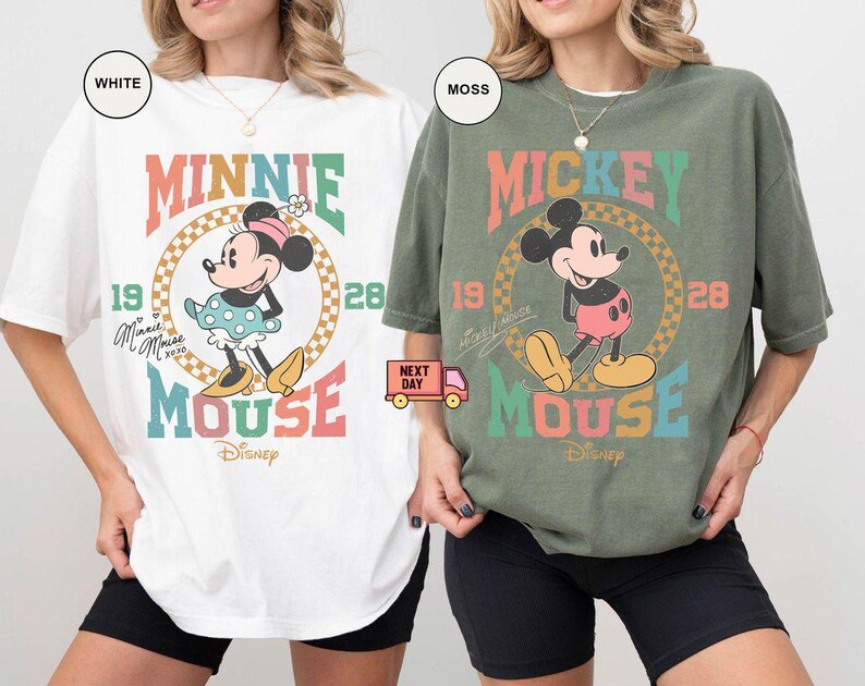 May include: Two t-shirts featuring vintage-style illustrations of Mickey and Minnie Mouse. The Mickey Mouse shirt is moss green with the text "Mickey Mouse" in rainbow colors. The Minnie Mouse shirt is white with the text "Minnie Mouse" in rainbow colors.