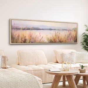 a living room with a white couch and a painting on the wall
