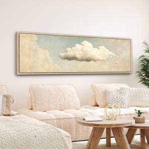 May include: A long, horizontal canvas painting of a single, fluffy white cloud against a light blue and beige sky. The painting is framed in a light wood frame.