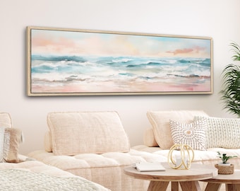 May include: A long, horizontal painting of a seascape with a light pink, blue, and white color scheme. The painting depicts a beach with waves crashing on the shore. The painting is framed in a light wood frame.