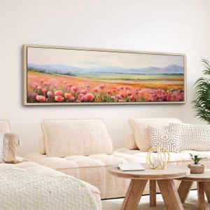 Puede incluir: Una pintura de lienzo larga y horizontal que representa un campo de flores rosas en un entorno paisajístico. Las flores están en primer plano, con una cordillera distante en el fondo. El cielo es de un azul suave con nubes blancas.
