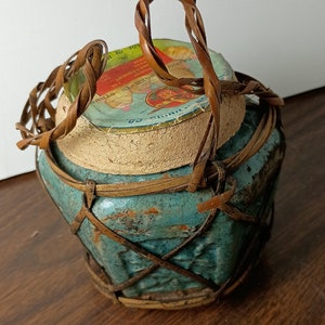 May include: A blue ceramic jar with a woven bamboo lid and handle. The jar has a label that reads "ONGKOKO" and "PURE INCHOLESTEROL FREE SOY SAUCE".