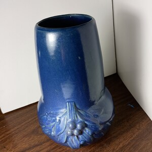May include: A blue ceramic vase with a floral design. The vase has a rounded body and a wide opening.
