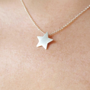 Puede incluir: Un collar de cadena de plata con un colgante de estrella simple.