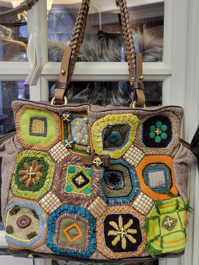 Puede incluir: Un bolso de mano de patchwork marr&oacute;n con cuadrados de ganchillo de colores y una correa de cuero marr&oacute;n.