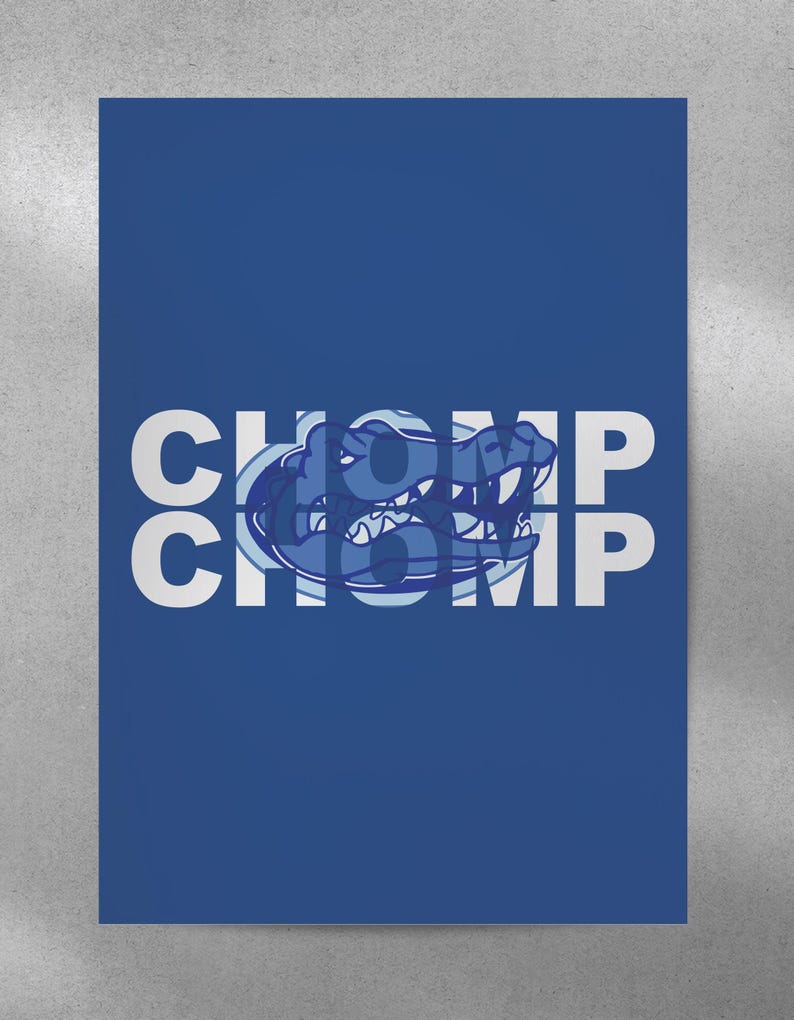 May include: A blue and white graphic design with the word "CHOMP" repeated twice. The graphic features a stylized alligator head with a blue and white color scheme.