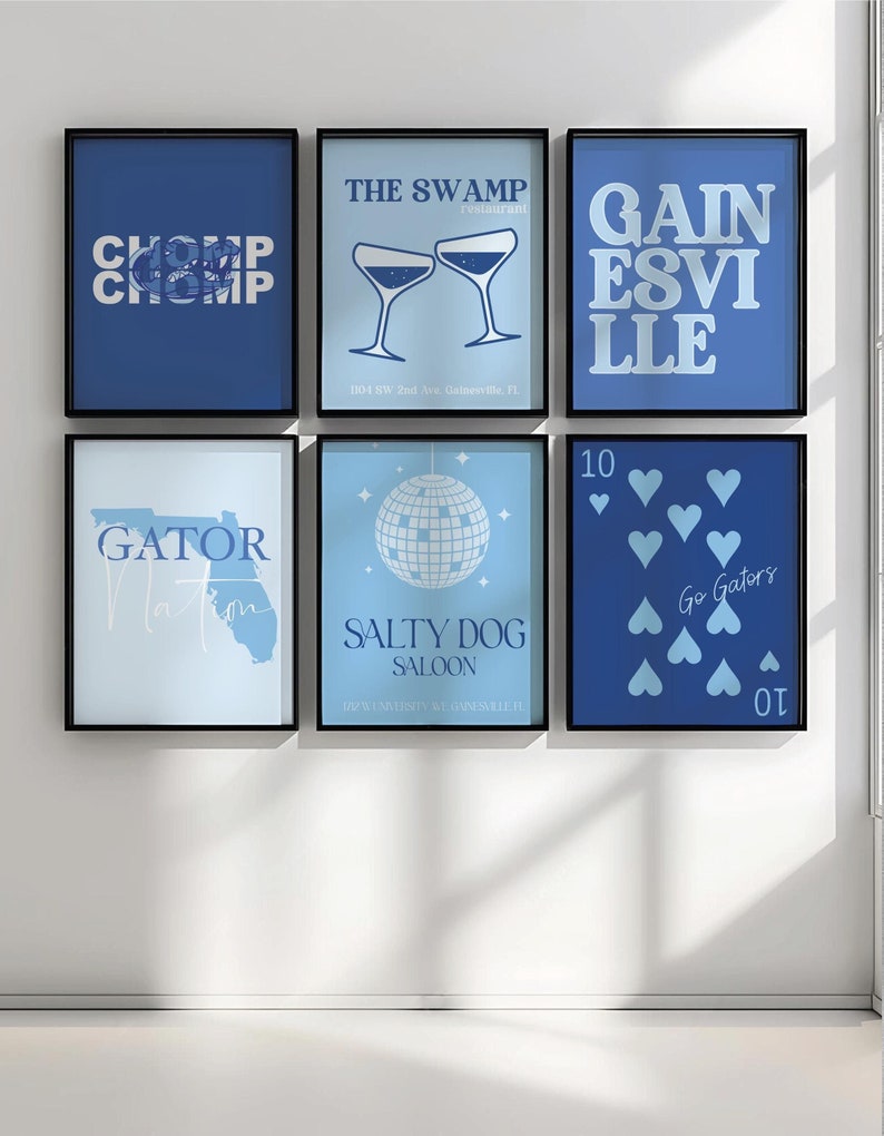 May include: A set of six blue and white framed prints with various designs related to the University of Florida Gators. The prints include the words "CHOMP CHOMP", "THE SWAMP", "GAINSEVILLE", "GATOR NATION", "SALTY DOG SALOON", and "Go Gators".