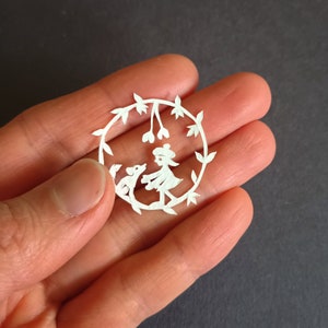 Boina Pom Pom menina e cachorro, arte original em papel cortado à mão em tamanho de moeda, arte japonesa cortada em papel Kiri-e, 1,25&quot; (30 mm) de diâmetro