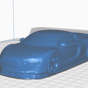May include: A blue 3D-printed model of a sports car, showcasing the vehicle's sleek design. The model is on a grid surface, with the text "UltiMaker S8" visible in the background. The car's wheels and body are clearly defined.