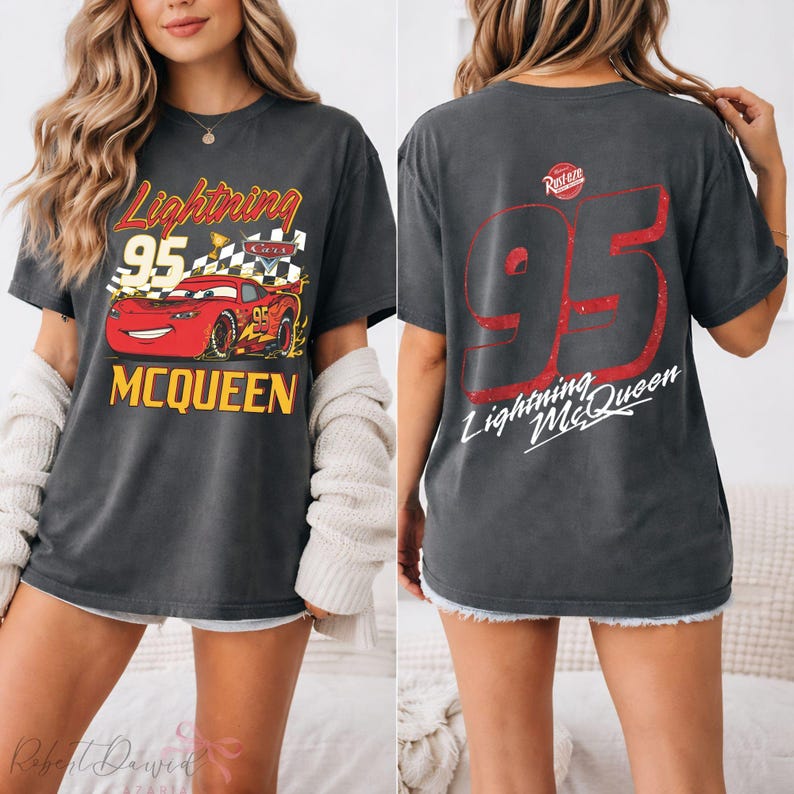 May include: Dark gray t-shirt featuring Lightning McQueen from the Cars movie. The front graphic shows McQueen with the number 95 and the text "Lightning McQueen". The back of the shirt has a large red number 95 and the text "Lightning McQueen".
