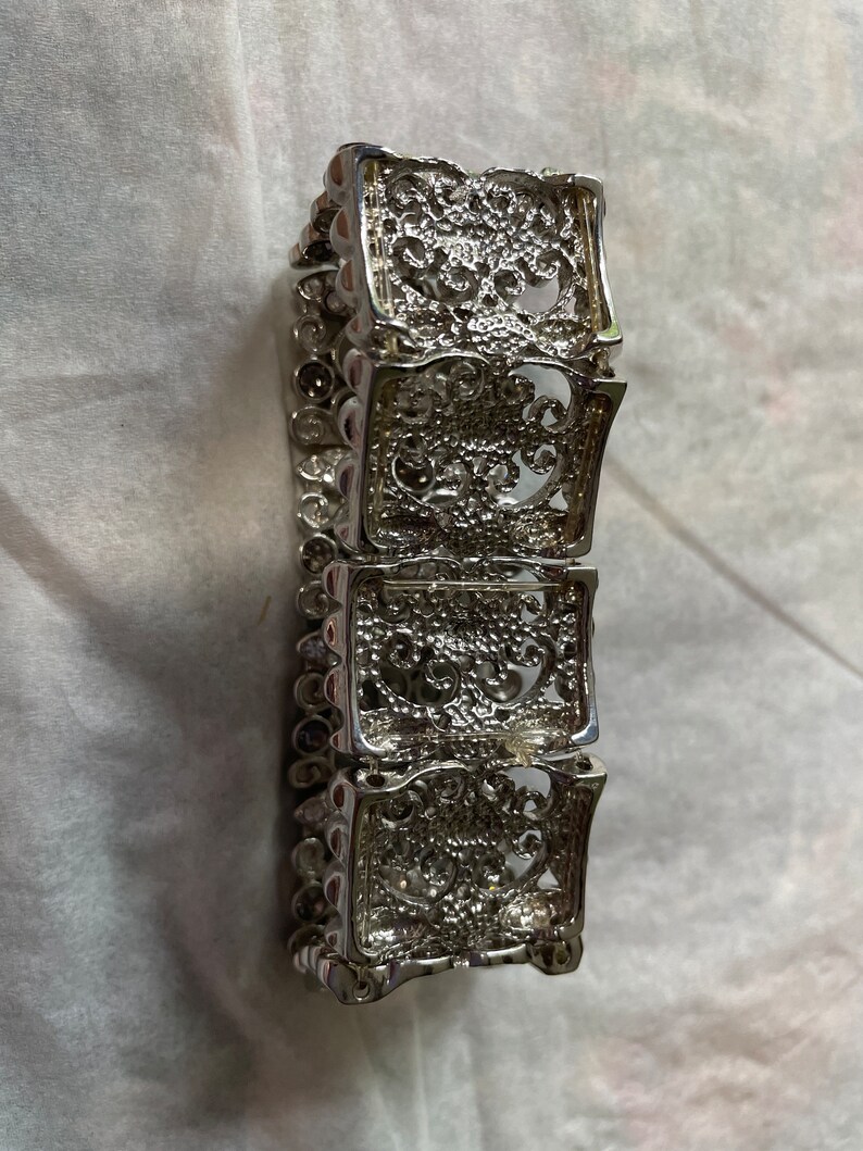 Pu&ograve; includere: Un braccialetto d'argento con un designo a filigrana. Il braccialetto &egrave; composto da quattro sezioni, ognuna con un motivo diverso. Il braccialetto &egrave; largo circa 5 cm.