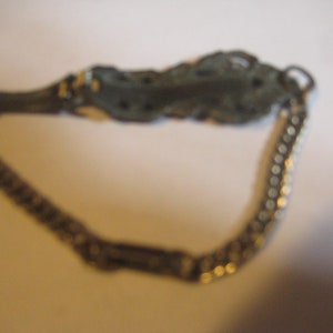 Puede incluir: Un brazalete de cadena de plata con un dije decorativo, adornado, de plata en forma de hoja.