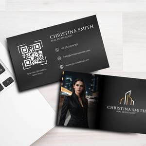 May include: Black and white business card with a QR code, contact information, and the text "CHRISTINA SMITH REAL ESTATE AGENT". The back of the card features a photo of a woman in a black blazer and a gold building logo with the text "CHRISTINA SMITH REAL ESTATE AGENT".