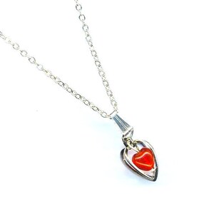 May include: A silver chain necklace with a double heart pendant. The inner heart is red.