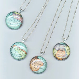 May include: Four silver necklaces with round glass pendants featuring vintage world maps. Each pendant depicts a different continent: South America, Africa, North America, and Europe.
