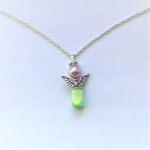 May include: A silver chain necklace with a green glass bead and a silver angel charm with a pink pearl on top.