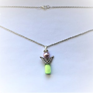 May include: A silver chain necklace with a pendant featuring a small angel with wings, a light green body, and a pink pearl head.