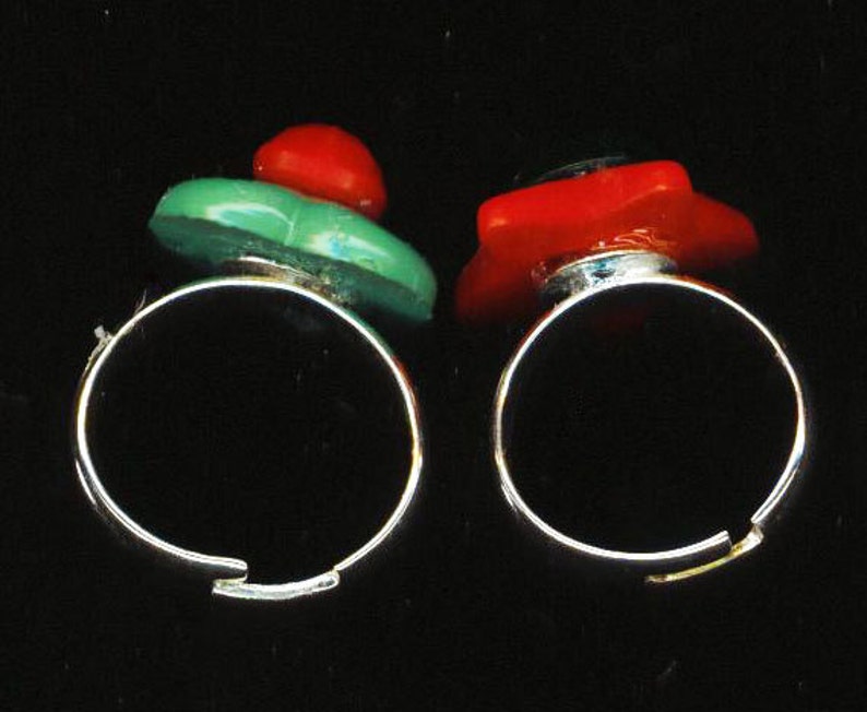 May include: Two silver rings with red and green glass stones. The rings are simple and elegant.