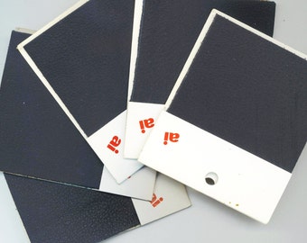 May include: Five black fabric swatches with white borders and the word "ai!" printed in red on each.