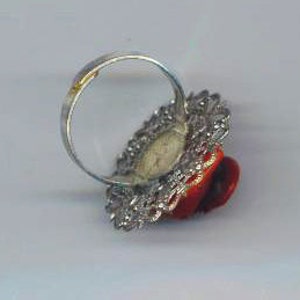 Puede incluir: Un anillo de cabuj&oacute;n rojo con un engaste de filigrana plateada. El anillo est&aacute; sobre un fondo blanco.